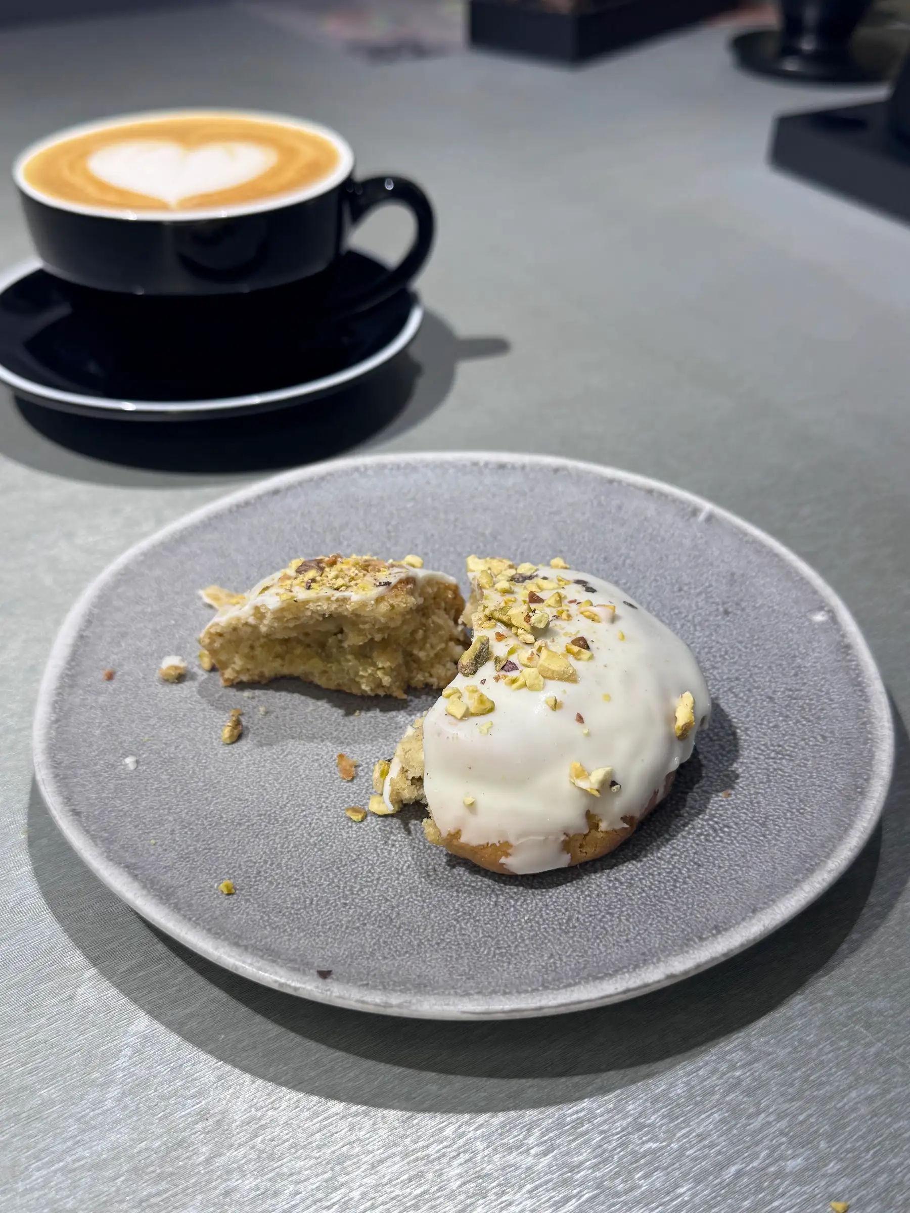 Galleta de chocolate blanco y pistacho junto a un latte