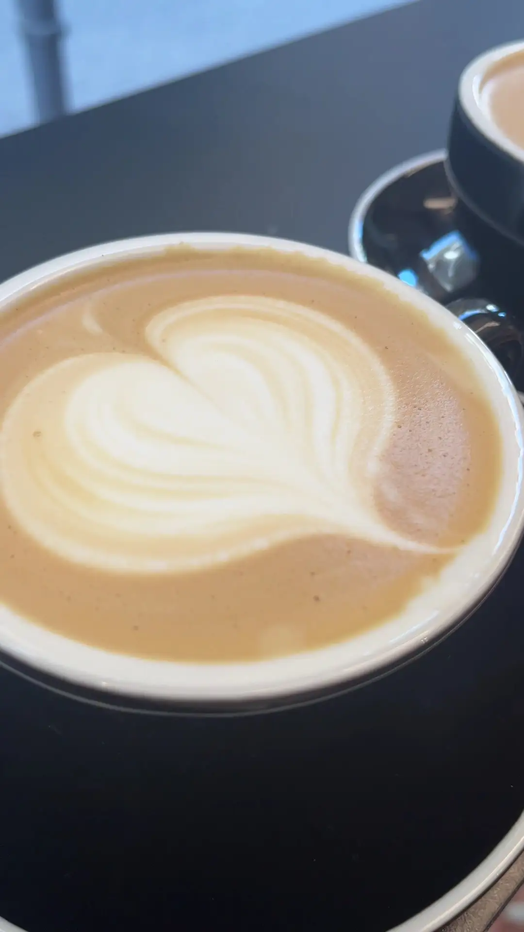 Latte con un corazón dibujado en la espuma, en taza negra